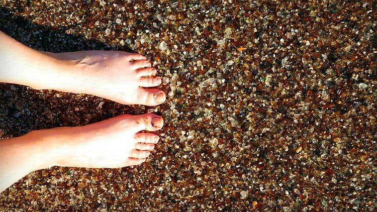 bare feet on sea glass beach