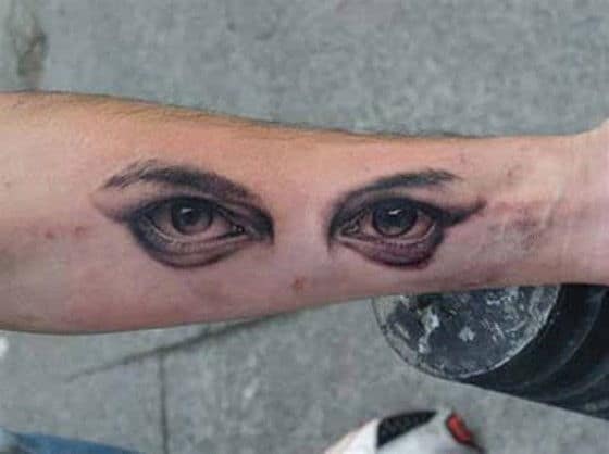 Tattoo of face and eyes on the arm