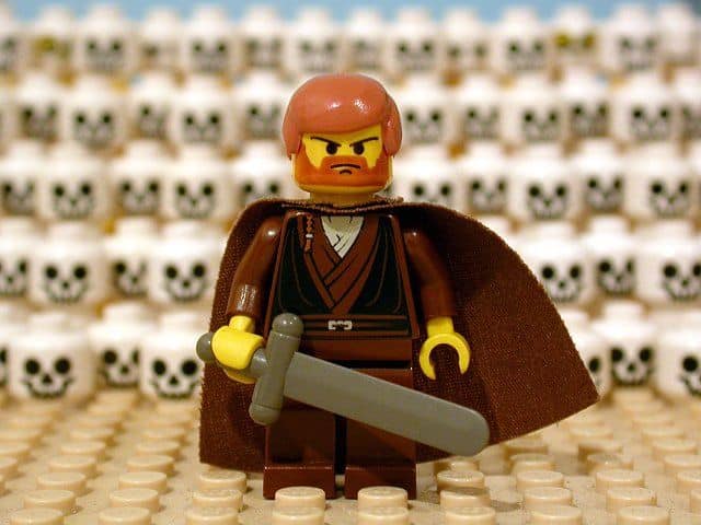 lego man standing in front of a wall of skulls