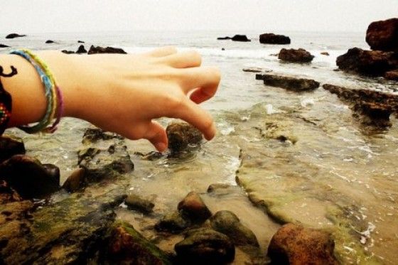Perfectly Timed Photos picking large rock from beach
