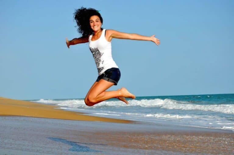 happy young woman jumping on beach enlarged
