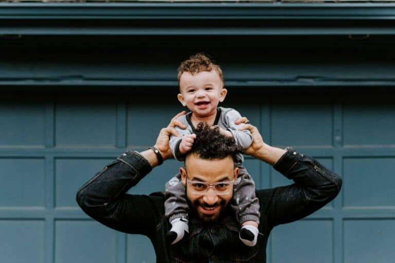 man holding child on shoulders