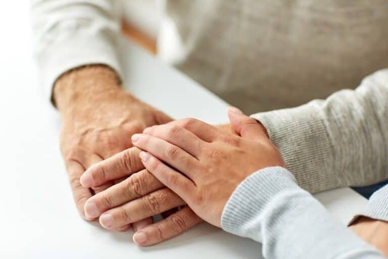 close up of old man and young woman holding hands