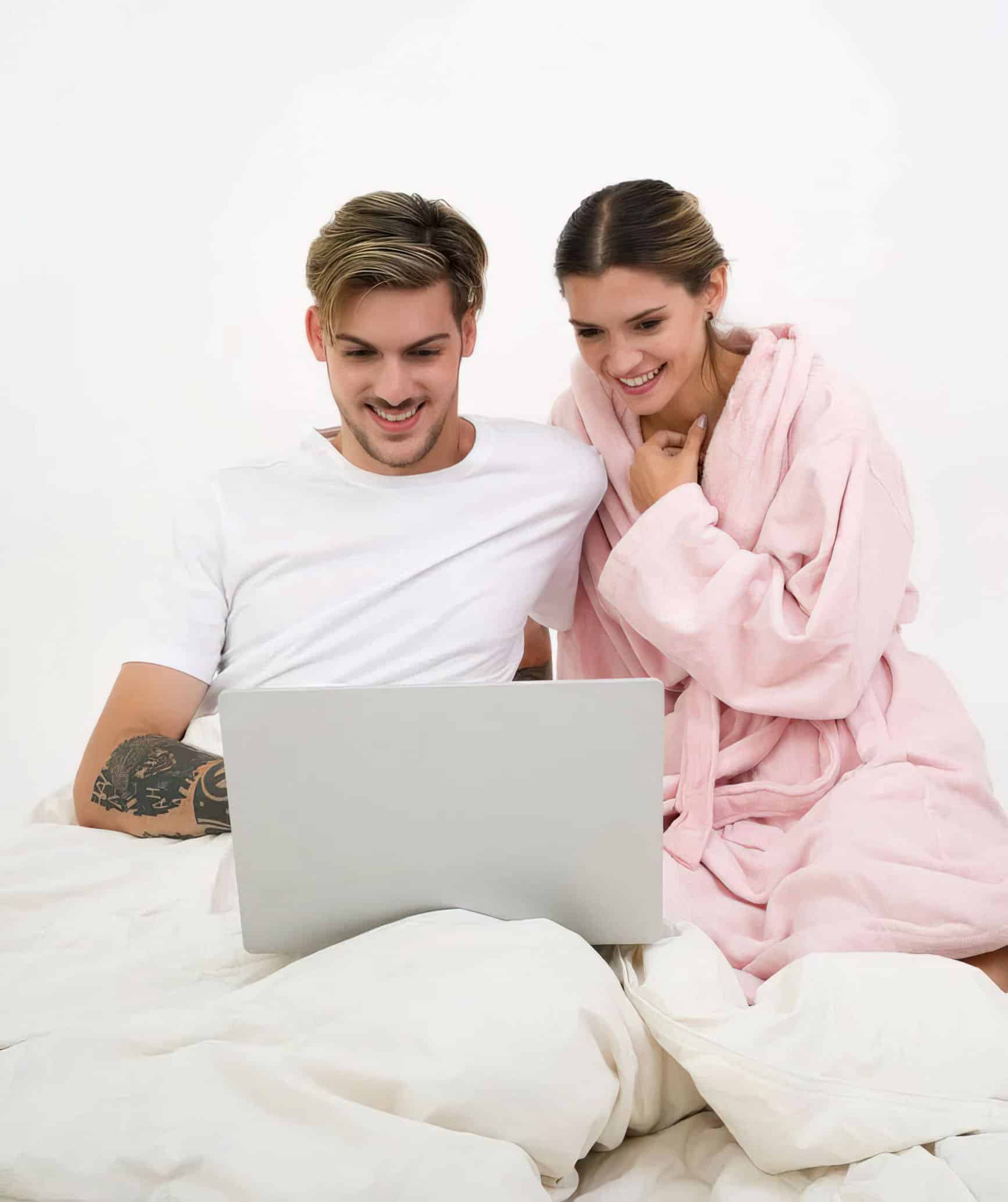 couple in bed smiling at computer
