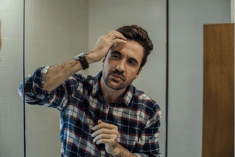 man checking his hair line in the mirror