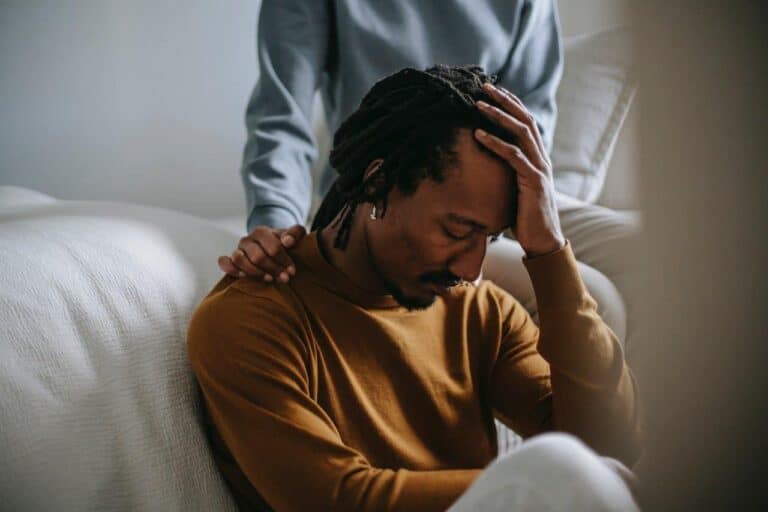 sad man leaning against bed