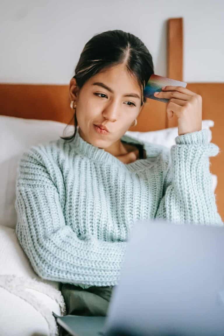 woman looking at computer and holding credit card