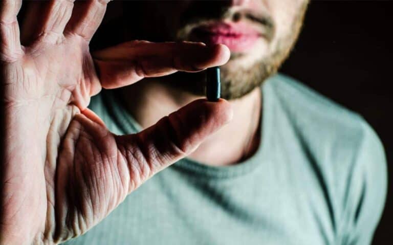man holding black pill