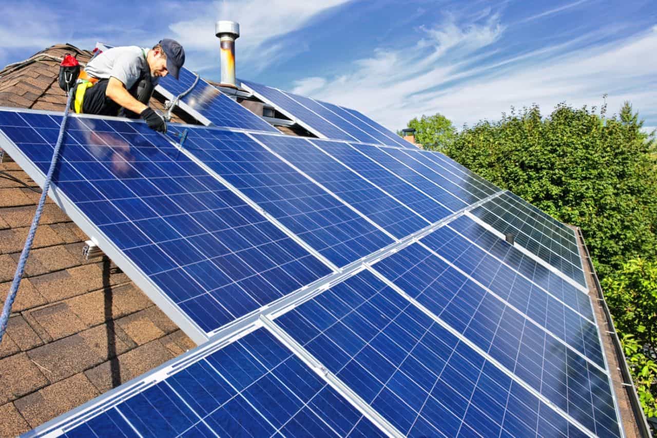 man installing solar panels on a roof