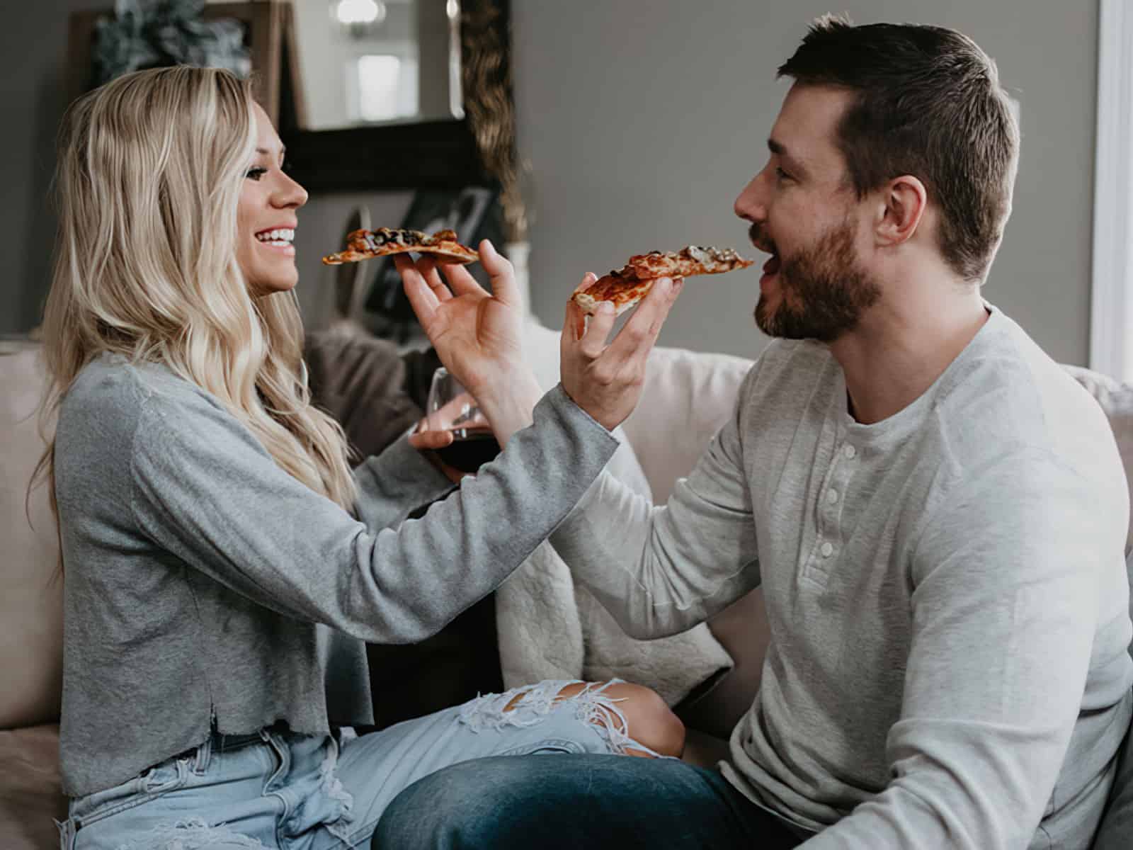 couple feeding each other pizza