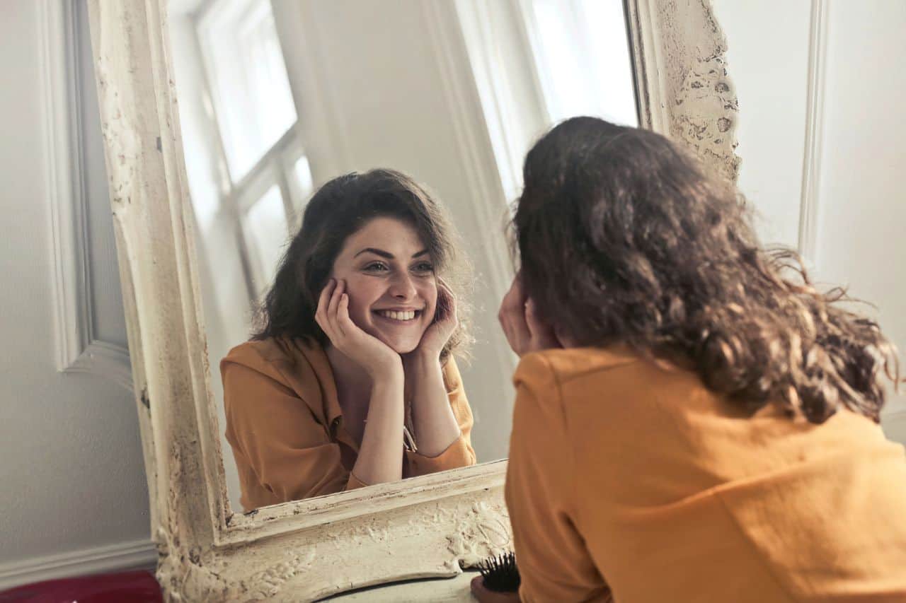 woman smiling into mirror