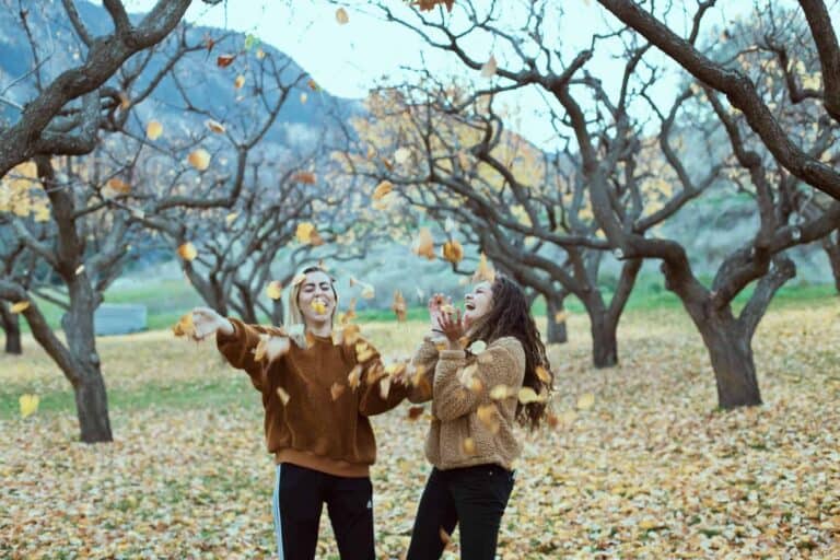women wearing sweaters fall leaves