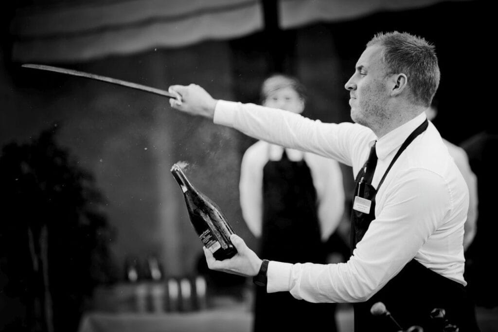 How to Safely Saber Champagne: A Step-by-Step Guide 2 man sabering bottle of champagne