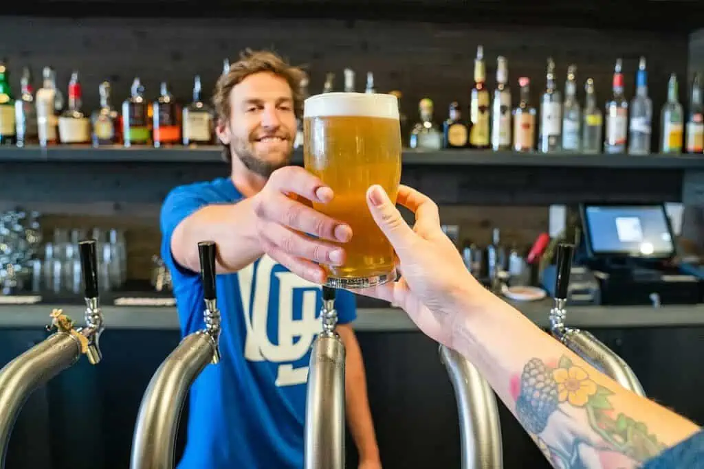 Can Bartenders Drink on the Job? Navigating Murky Laws and Regulations 2 bartender handing patron a beer
