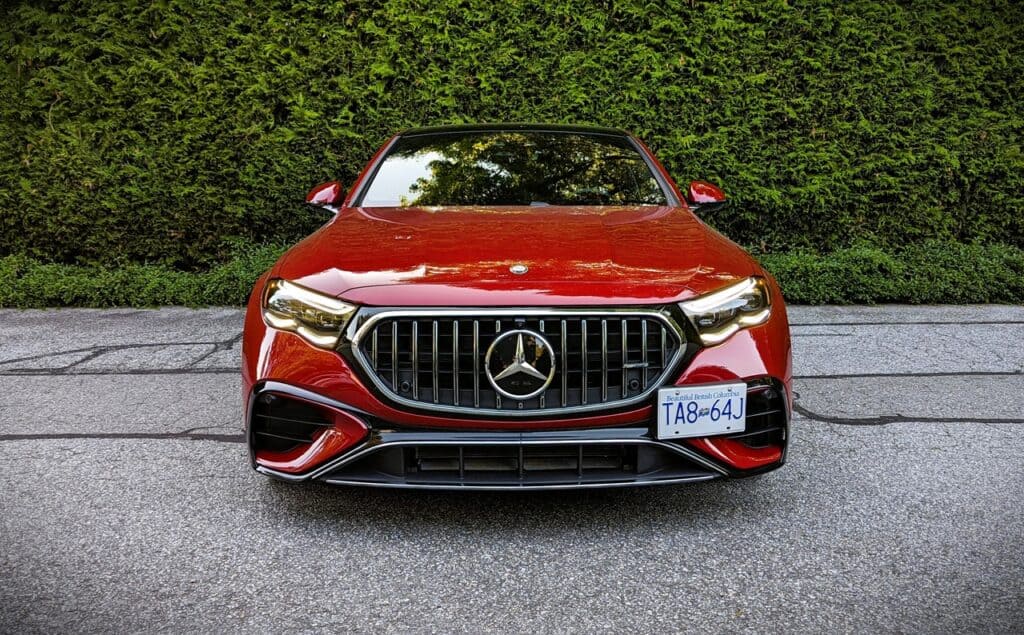 Luxury red Mercedes-Benz car parked on driveway with lush green hedge background, showcasing modern automotive design and high-performance features.