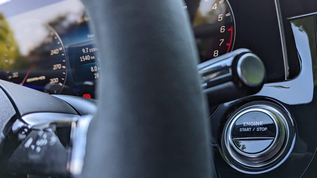 Luxury car dashboard close-up showing speedometer and engine start/stop button, modern vehicle interior, high-tech automotive design, automotive lifestyle, car enthusiast essentials.