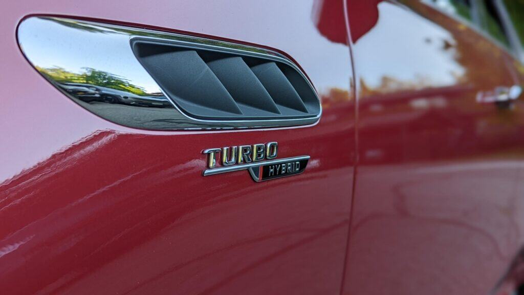 Turbo hybrid badge on red sports car, close-up detail of vehicle engine technology, high-performance automotive design, modern turbocharged hybrid engine, automotive innovation and engineering.