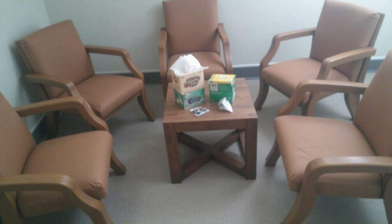 A cozy, lived-in room features casual seating and a small table with worn tissue boxes, inviting informal gatherings.