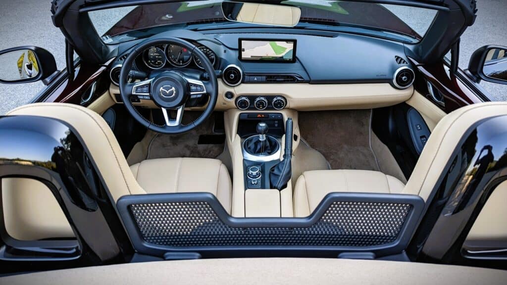 High-end convertible car interior showcasing steering wheel, navigation screen, and beige leather seats, perfect for automotive enthusiasts and luxury vehicle aficionados.
