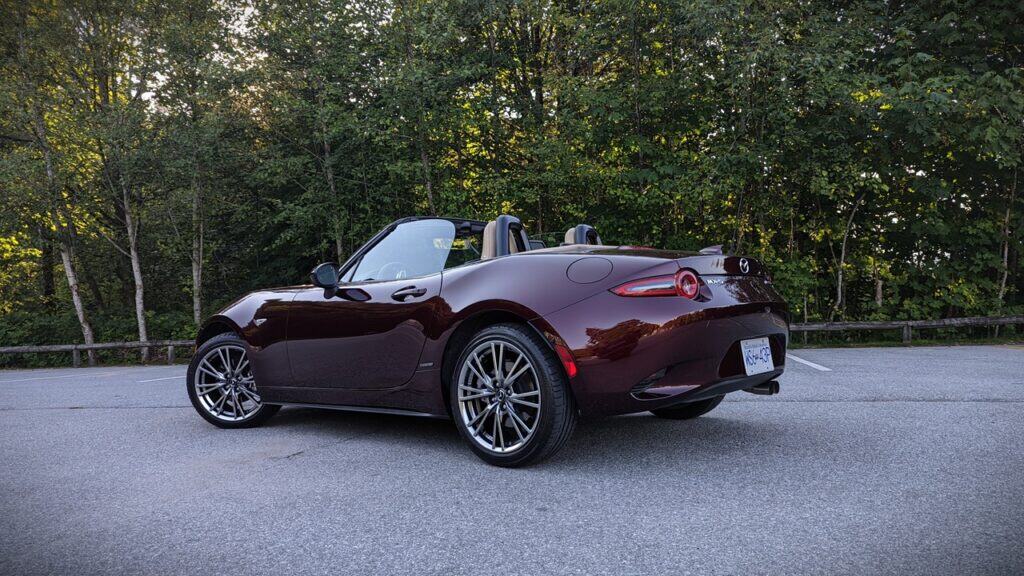 Convertible sports car parked on a scenic road with lush greenery background.
