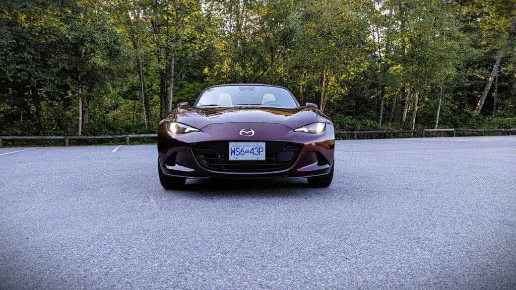 Convertible sports car parked on a road surrounded by greenery, showcasing sleek design and modern style.