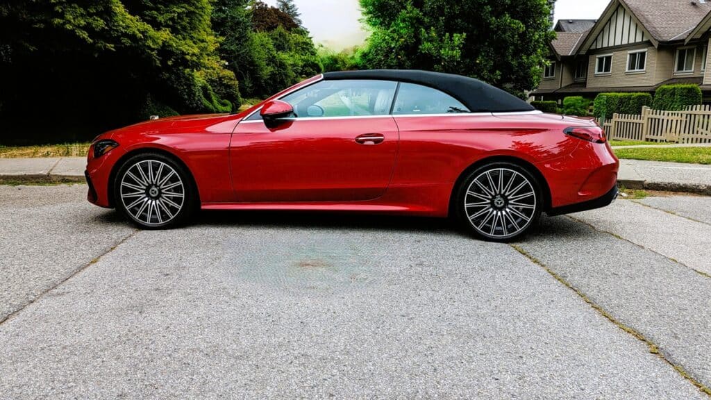 2025 Mercedes-Benz CLE 300 4MATIC Cabriolet Review 9 Red convertible sports car parked on residential street with lush green trees and houses in the background.