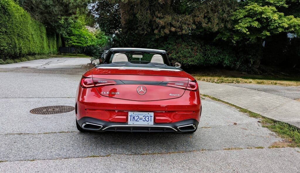 2025 Mercedes-Benz CLE 300 4MATIC Cabriolet Review 8 A sleek red Mercedes-Benz convertible parked on a quiet residential street surrounded by lush greenery.