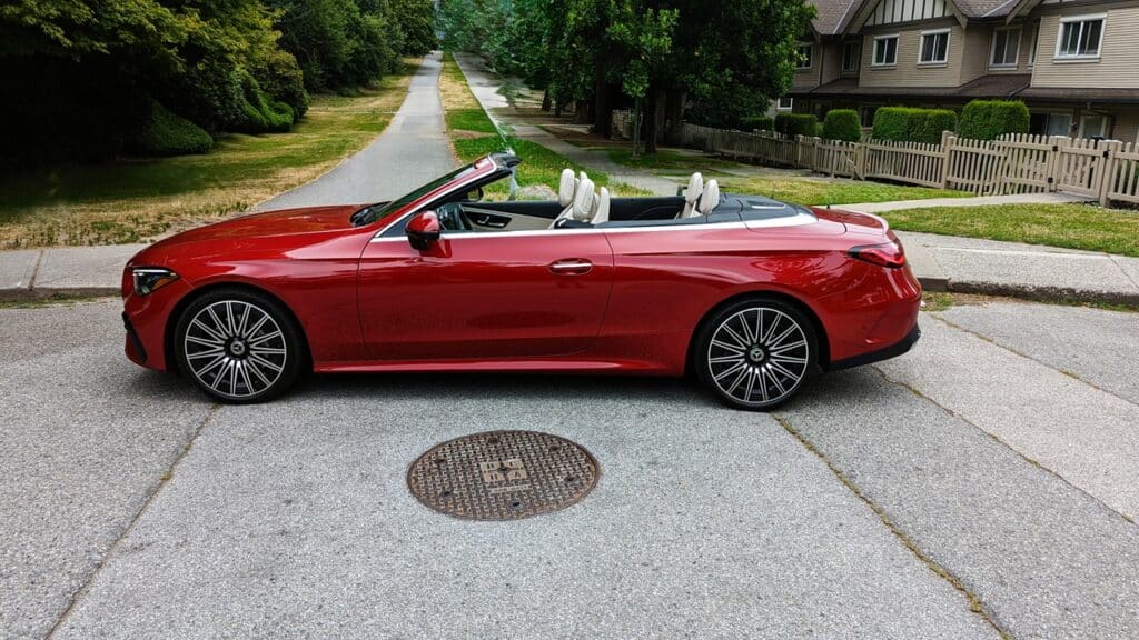 2025 Mercedes-Benz CLE 300 4MATIC Cabriolet Review 6 Red convertible sports car parked on residential street with trees and houses, showcasing luxury vehicles suitable for outdoor drives and leisure.
