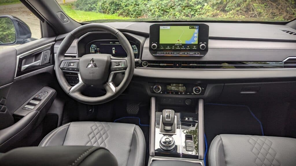 2025 Mitsubishi Outlander PHEV Noir Review 5 Black Mitsubishi vehicle interior with leather seats, advanced digital dashboard, and a navigation touchscreen mounted on the central console. The image highlights modern automotive tech and premium design.