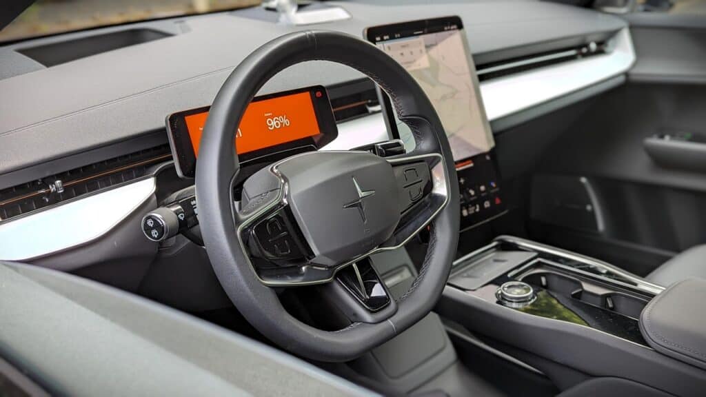 2025 Polestar 3 Long Range Dual Motor Review 9 A modern car interior with a digital dashboard, steering wheel, and infotainment system, showcasing advanced automotive technology and sleek design.