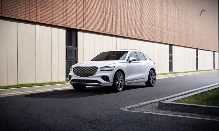 Luxury white SUV parked on city street with modern building background.