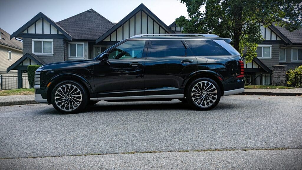 2026 Hyundai Pallisade Ultimate Calligraphy Review 5 Black luxury SUV parked on a residential street in front of modern houses, showcasing stylish design, 'Unfinished Man' branding, and appeal to automotive enthusiasts and discerning drivers.
