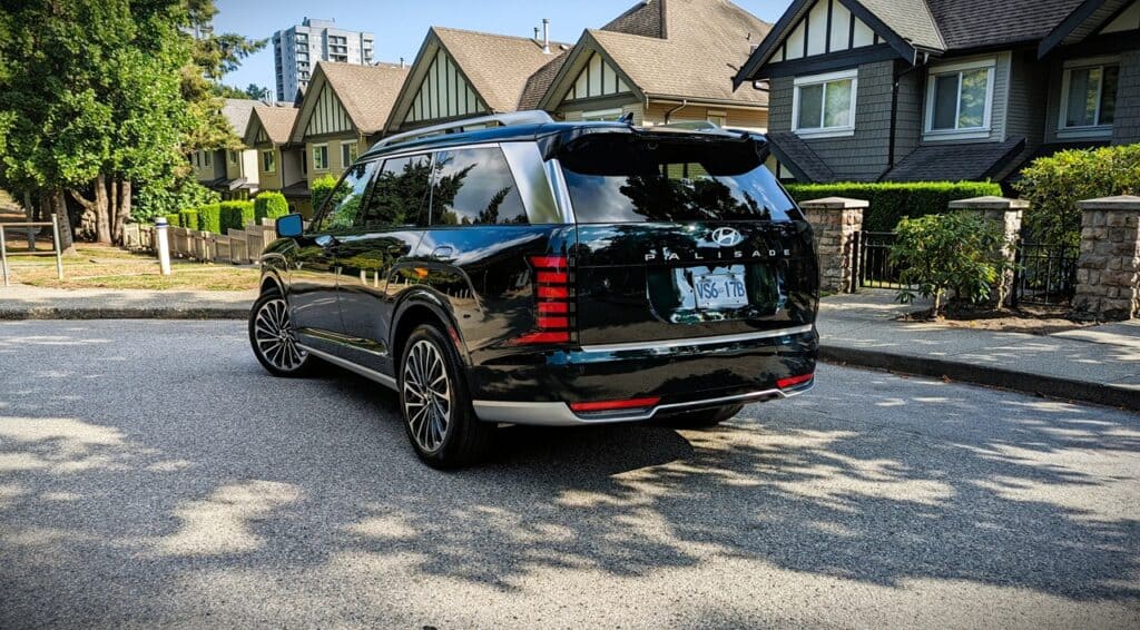 2026 Hyundai Pallisade Ultimate Calligraphy Review 11 Luxurious black Hyundai Palisade SUV parked on residential street with modern houses and greenery in the background.