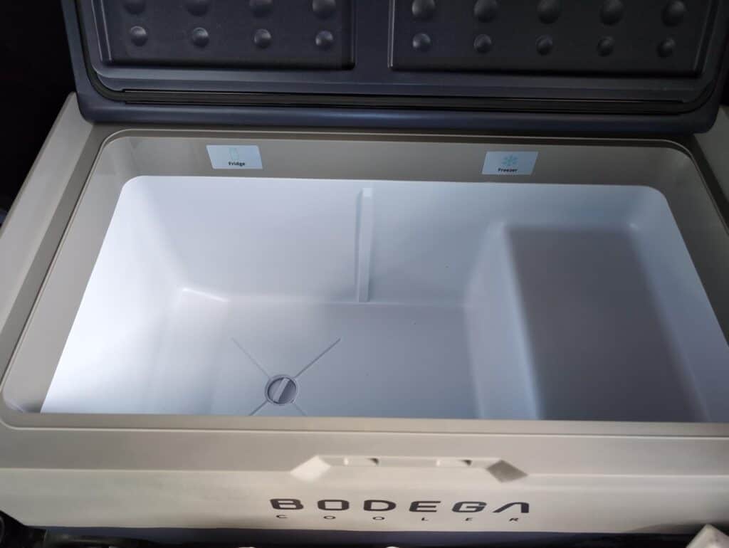 BODEGAcooler 36L Dual Zone 12V Portable Car Fridge Review 12 Empty white chest freezer with labeled sections for fridge and freezer, inside view.