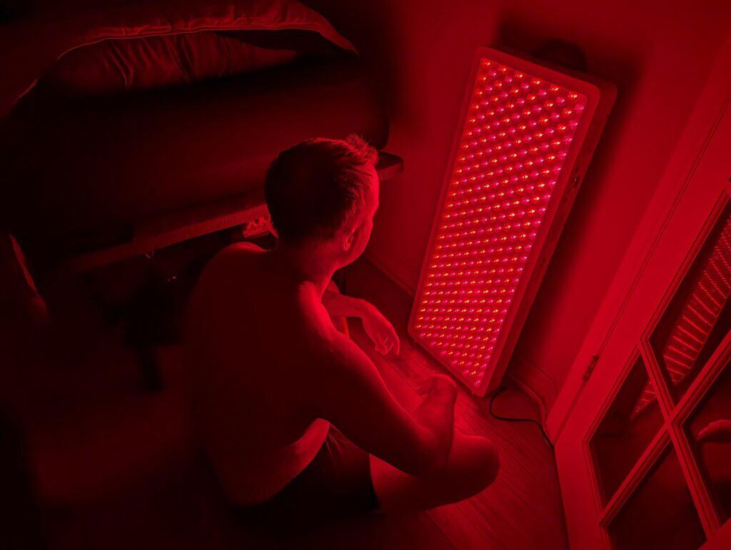 BestQool Red Light Therapy Pro300 Review: 9 Bright Benefits 11 Red LED light therapy device used for skin treatment or mood enhancement in a dimly lit room.