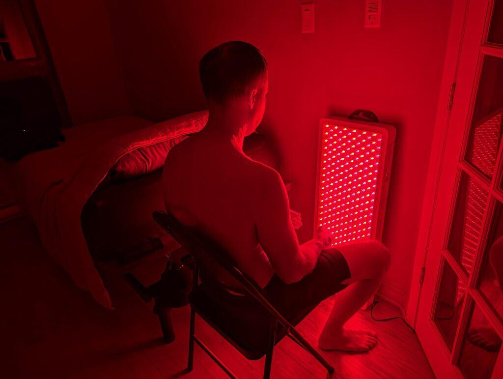 BestQool Red Light Therapy Pro300 Review: 9 Bright Benefits 12 Red LED light therapy device for men's health and wellness, featuring a man sitting in a modern bedroom. Perfect for skin rejuvenation, mood enhancement, and male vitality routines.
