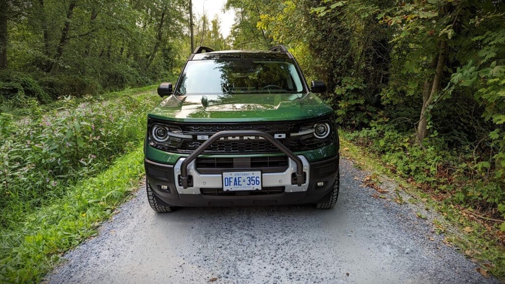 2025 Ford Bronco Sport Outer Banks Review 3 Off-road green SUV parked on a gravel trail in a dense forest setting with lush greenery.