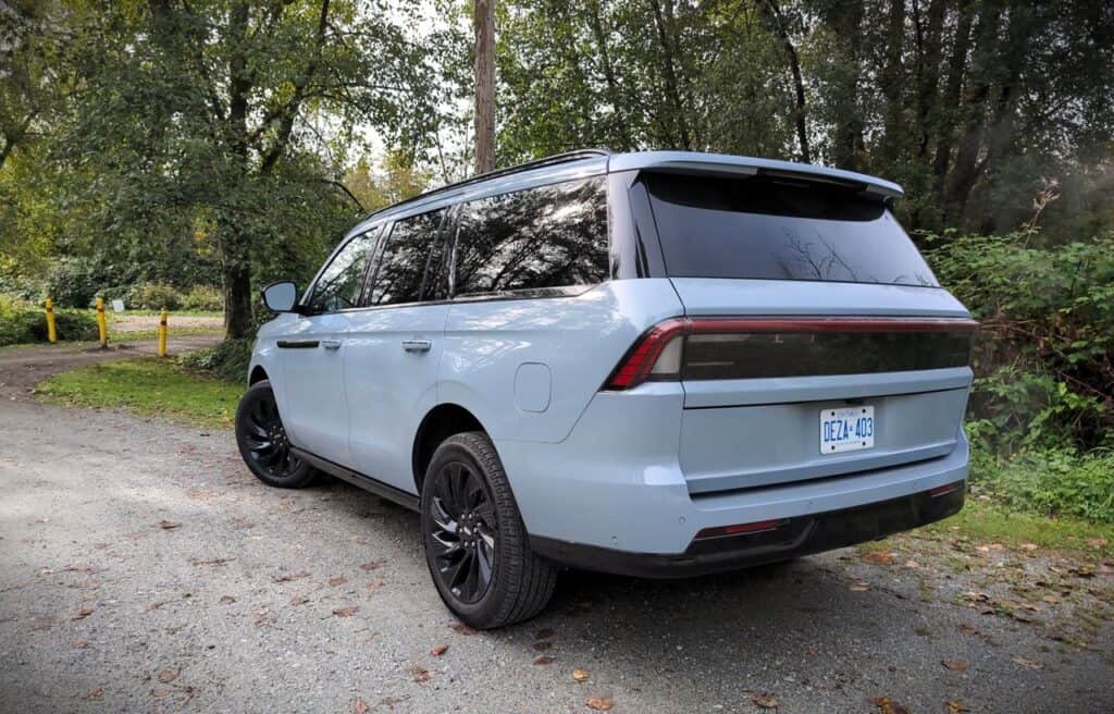 2025 Lincoln Navigator Reserve Review 7 Modern light blue electric SUV parked on a dirt road surrounded by green trees.