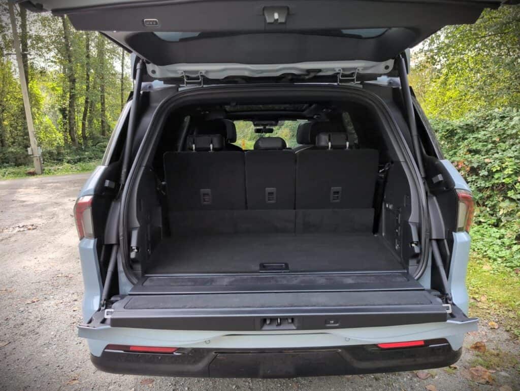 2025 Lincoln Navigator Reserve Review 9 High-resolution image of the open trunk of a modern SUV with a spacious cargo area, parked outdoors amidst greenery and trees, showcasing versatile storage space for outdoor adventures or daily use.