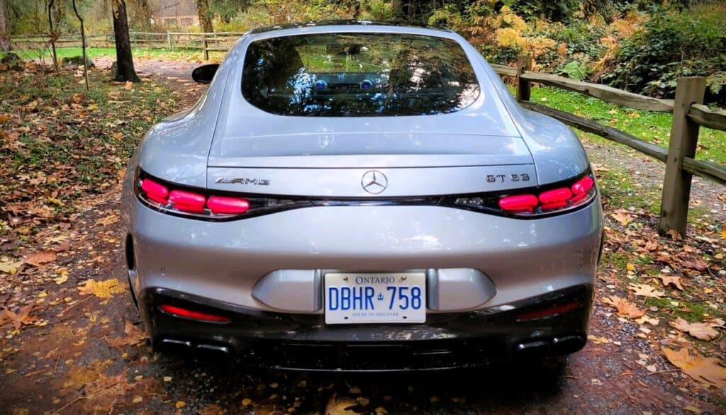 2025 Mercedes-AMG GT 63 4MATIC+ Coupe Review 12 Mercedes-Benz AMG GT 63 rear view, luxury sports car with sleek design, red taillights, and quad exhaust pipes parked on a forest trail during autumn.