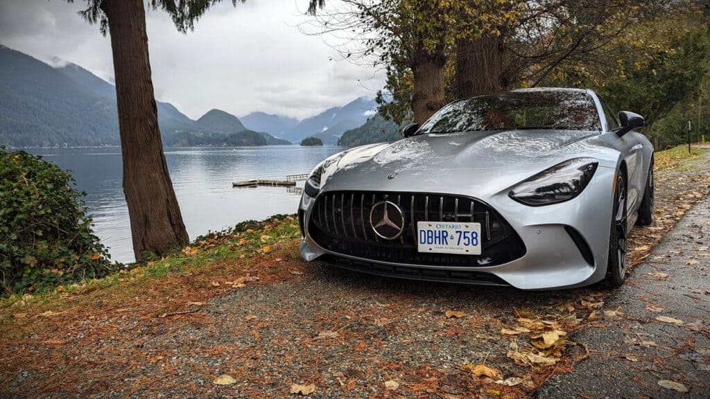 2025 Mercedes-AMG GT 63 4MATIC+ Coupe Review 9 Rusty Mercedes-Benz sports car parked by a scenic lake with mountains in the background.