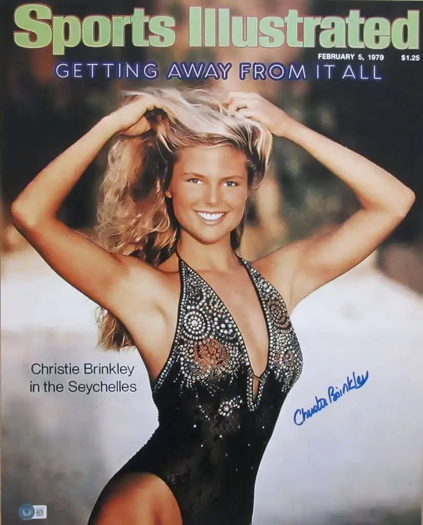 14 Hottest Sports Illustrated Swimsuit Covers of All Time 4 Portrait of a smiling woman with blonde hair, wearing a detailed black swimsuit, outdoors background with autumn colors, magazine cover style, signed by Christie Brinkley.