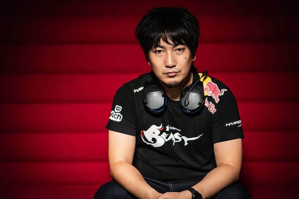 Daigo Umehara: The Legendary Beast's Complete Fighting Game Journey 2 Young male gamer with headphones, casual clothing, and a confident expression sitting against a red background; esports, gaming, and streamer lifestyle.