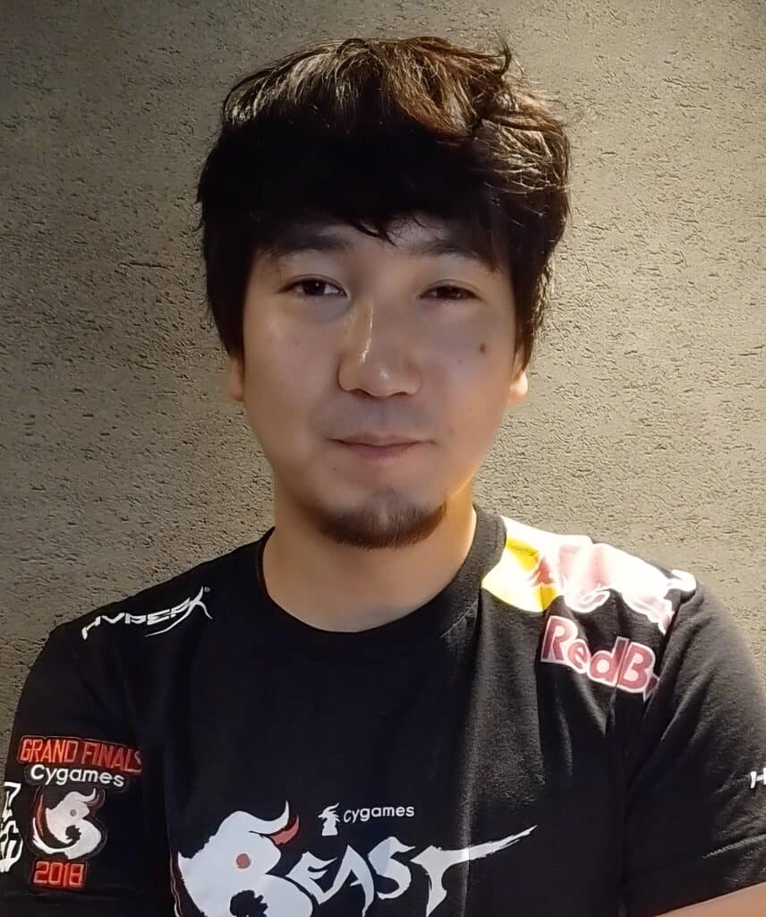 Daigo Umehara: The Legendary Beast's Complete Fighting Game Journey 7 Young man with dark hair and a slight smile, wearing a gaming jersey, in front of a textured wall.