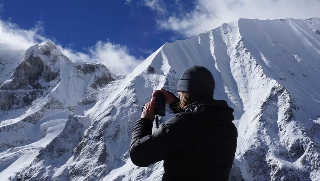 How Difficult Is Manaslu Trek? Challenges & Tips 2 Photographer taking photos of snow-covered mountain peaks during a clear day.