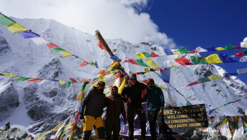 How Difficult Is Manaslu Trek? Challenges & Tips 3 Colorful prayer flags on Himalayan mountain pass with trekkers at 5106 meters altitude, representing adventure, mountaineering, and trekking in Nepal’s stunning snow-capped peaks.