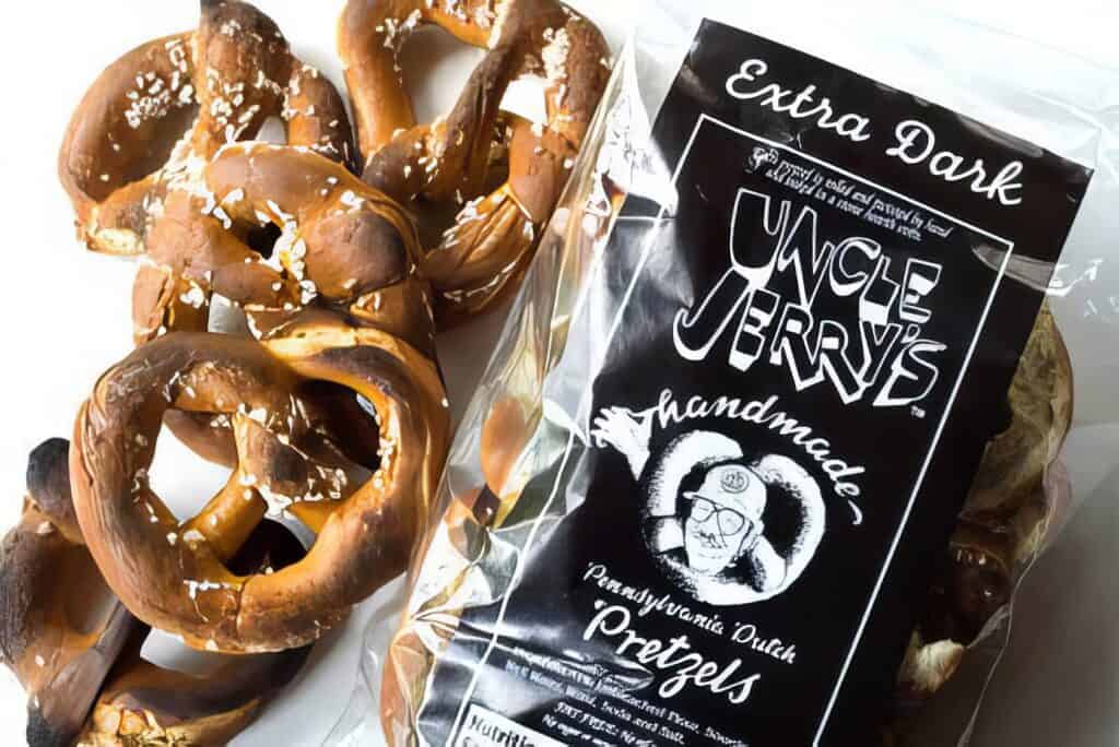 Why Uncle Jerry's Hand-Rolled Pretzels Are Beating Big Snack Giants—And Why You Might Ditch the Bag for the Batch 2 Wild foraged raw mushrooms with a bag of 'Extra Dark Uncle Jerry's Handcrafted Pretzels' on white background.