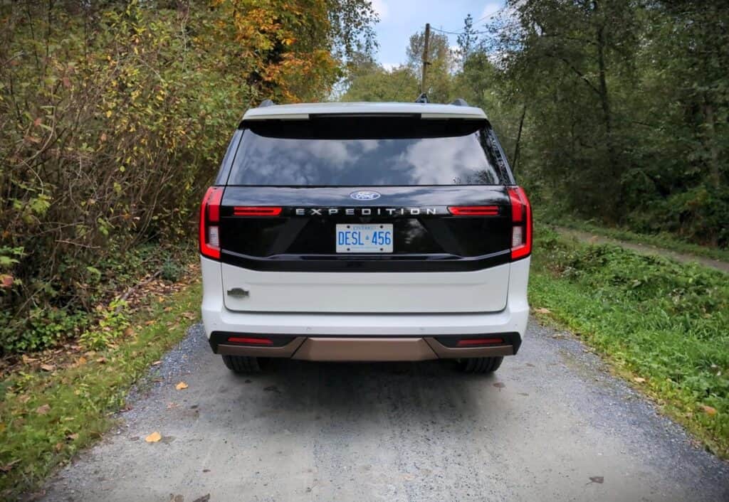 2025 Ford Expedition King Ranch Review 11 Modern Ford Explorer Expedition SUV parked on gravel road with autumn foliage and trees in background, showcasing spacious and stylish design for outdoor adventures.