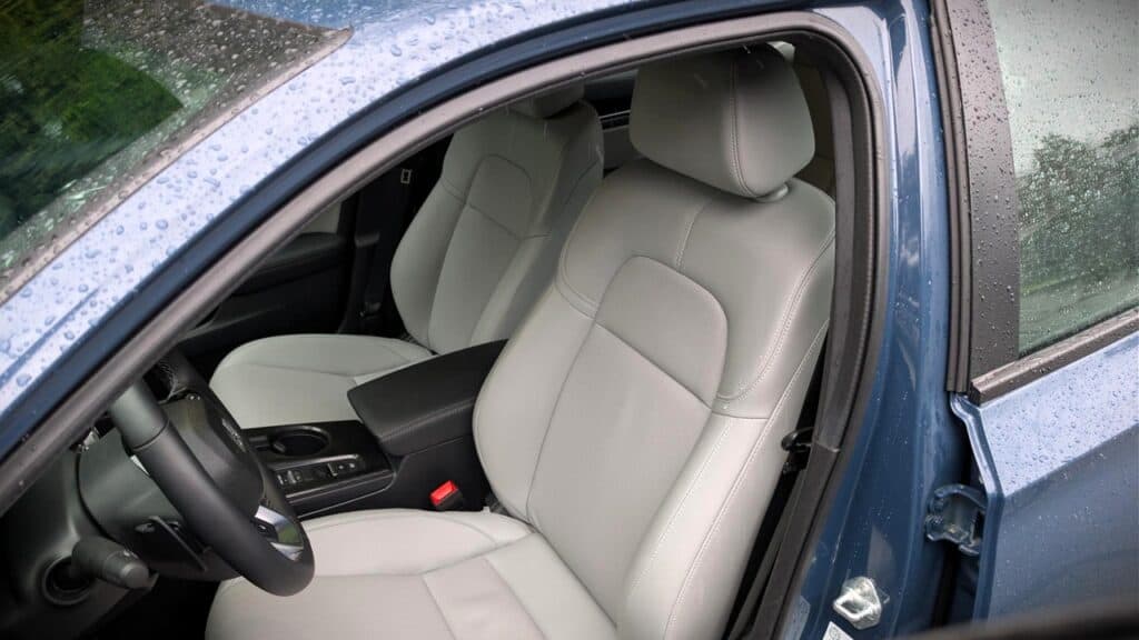 Interior of a modern car with beige leather seats and water droplets on the windshield, highlighting automotive comfort and design features.
