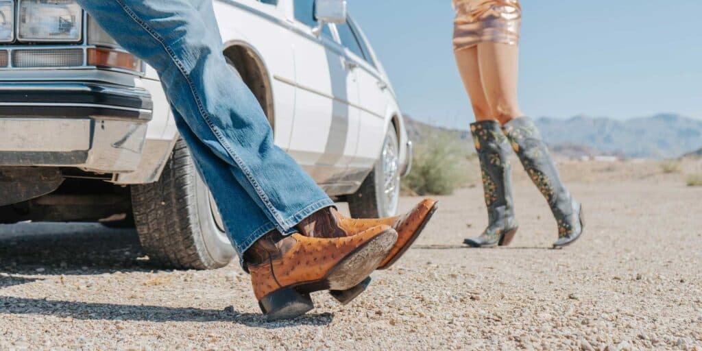 Stylish cowboy boots worn by a man and woman in a desert setting, showcasing trendy footwear and fashion style. The scene highlights adventure and eye-catching footwear, perfect for outdoor fashion photos.